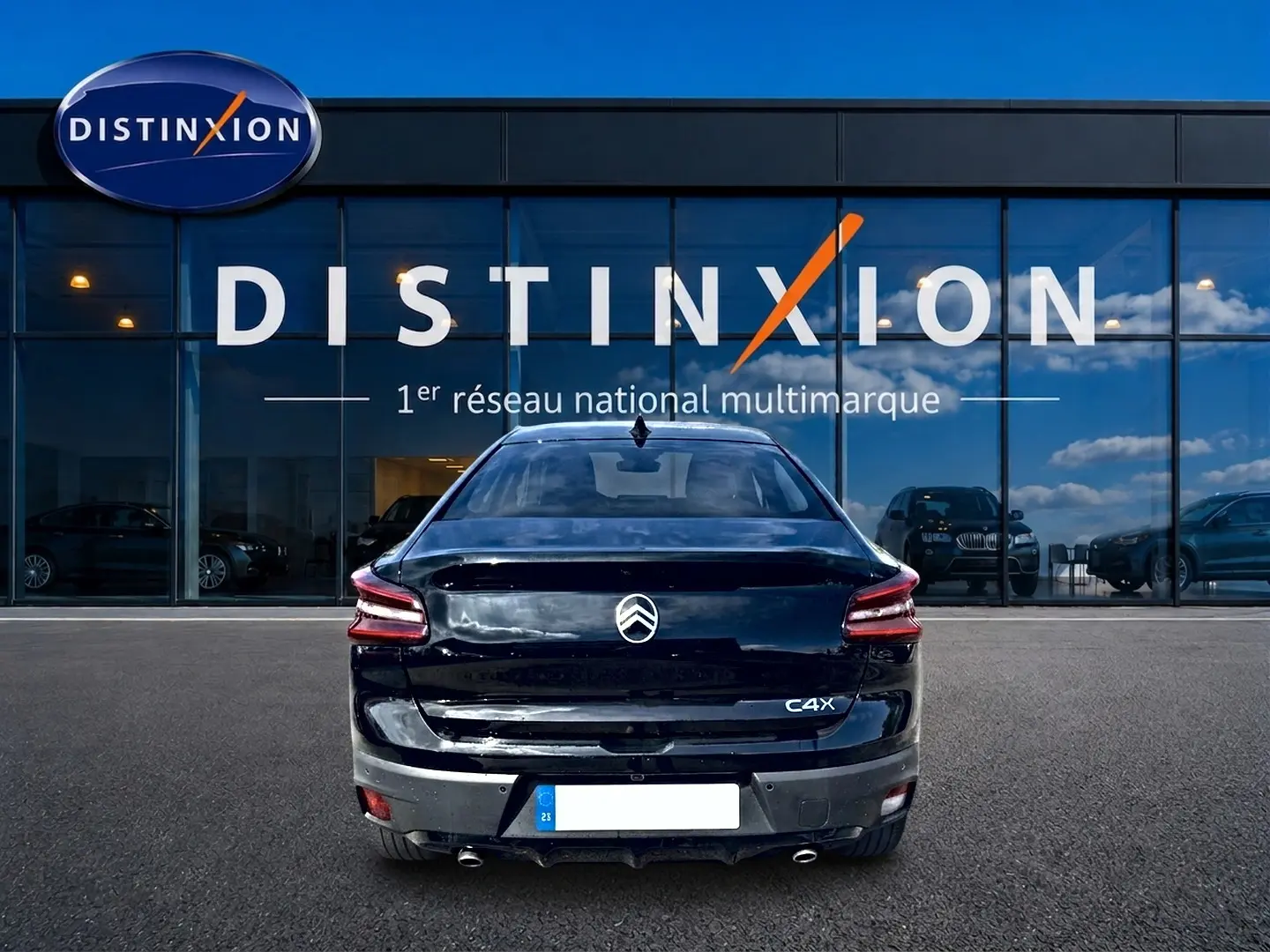 Vue arrière d'une Citroën C4 X noire 2025, avec feux LED et double sortie d'échappement chromée, devant un showroom.