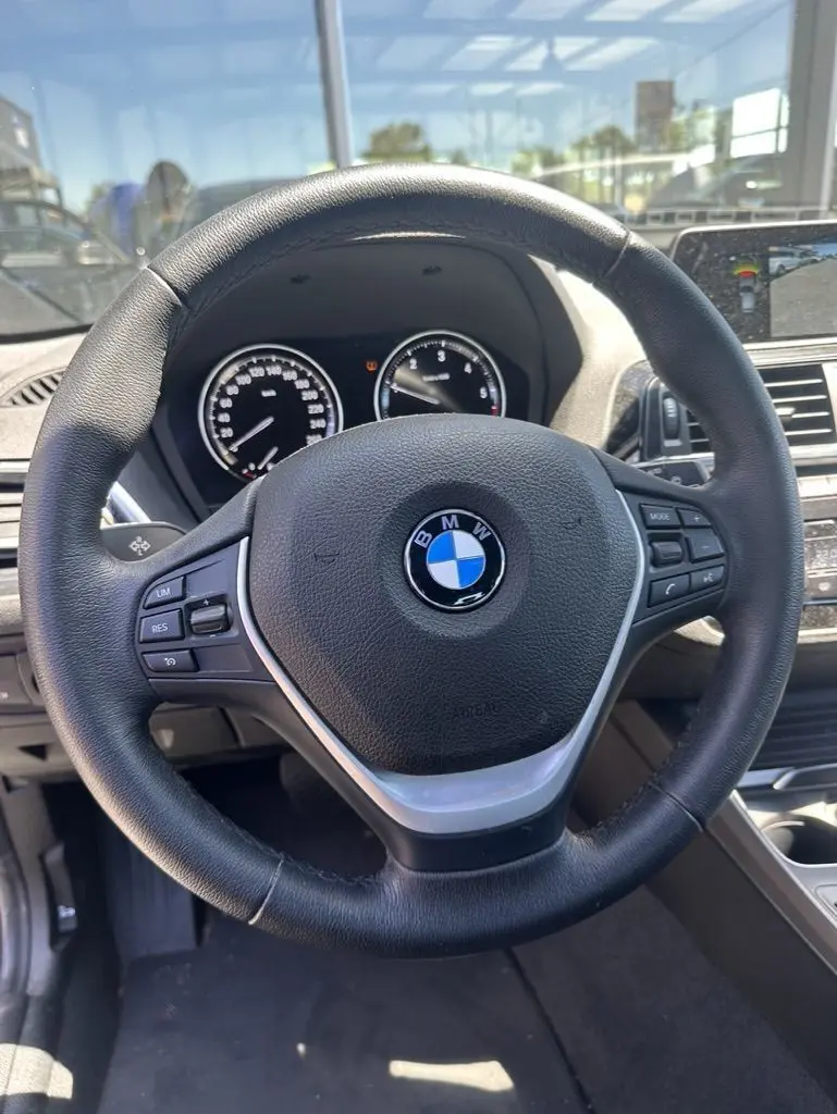 Vue rapprochée du volant noir de la BMW Série 1 F20 116D 2019 avec commandes intégrées et tableau de bord visible.