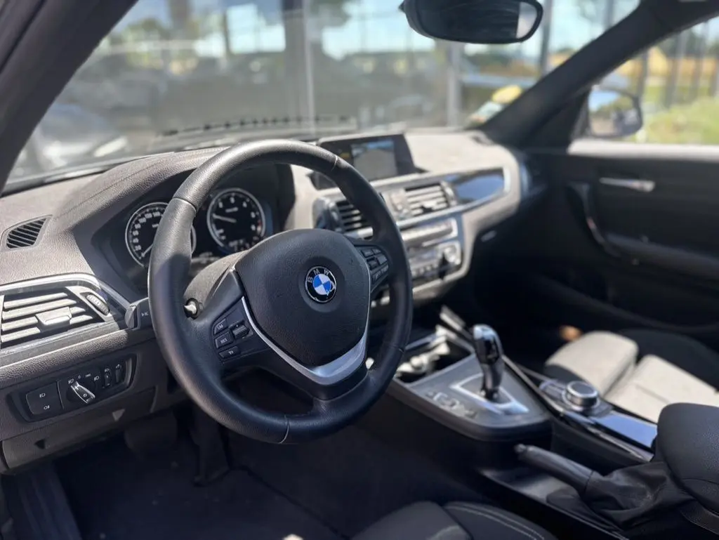Vue intérieure de la BMW Série 1 F20 116d 2019, montrant le volant, tableau de bord et console centrale en noir.