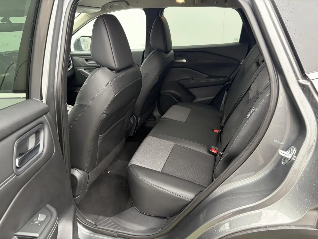 Vue côté droit de l'habitacle arrière du Nissan Qashqai III gris foncé, sièges mixtes cuir et tissu noirs.