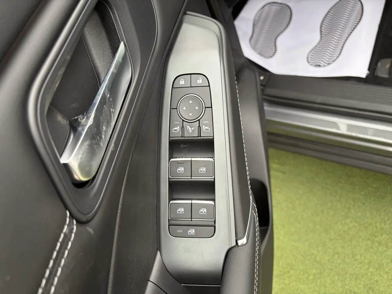 Vue rapprochée du panneau de commandes des vitres et rétroviseurs côté conducteur du Nissan Qashqai gris foncé.