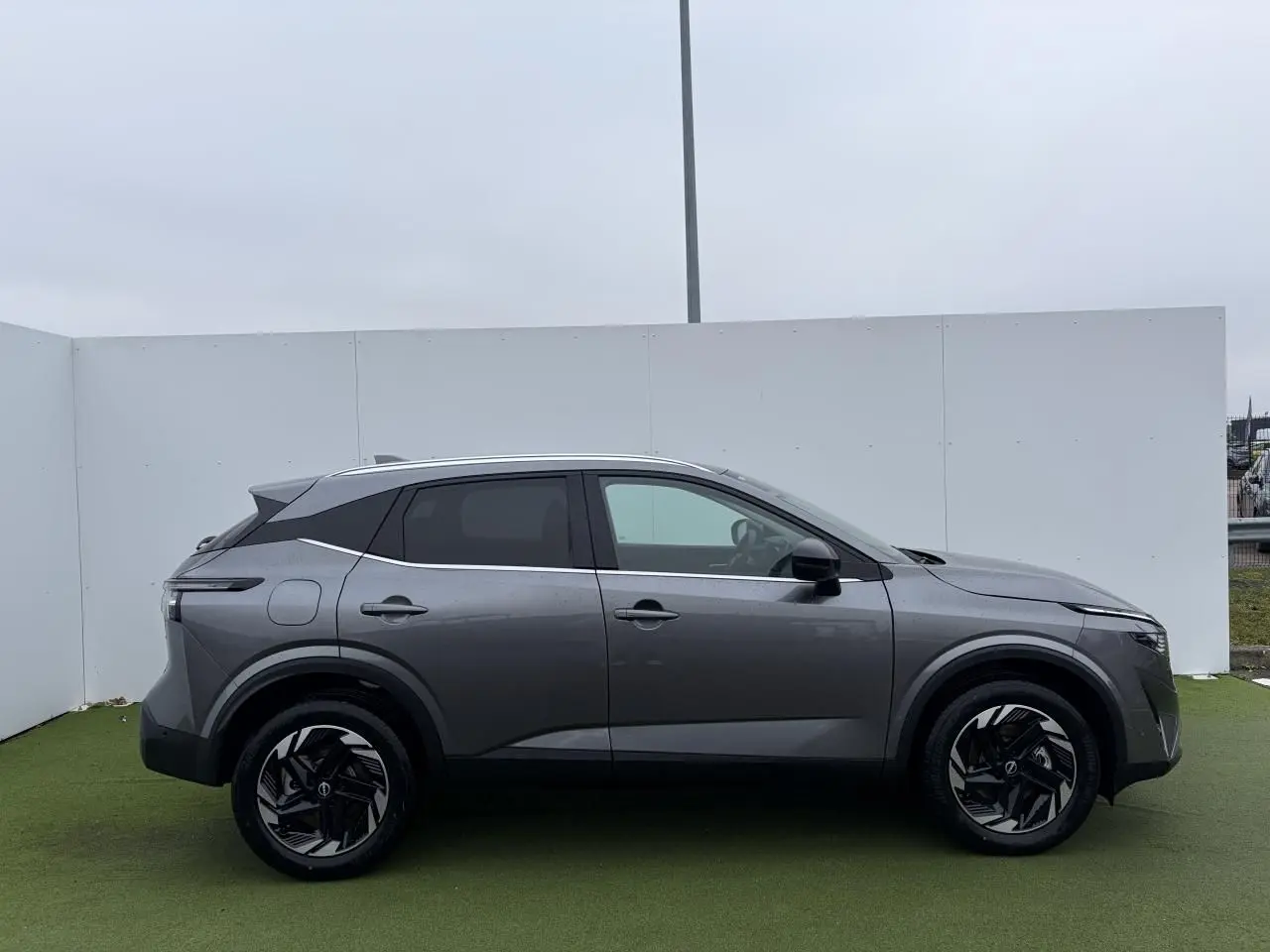 Vue de profil côté gauche du Nissan Qashqai III 1.5 Hybrid e-Power gris foncé métallisé avec jantes alliage noires.