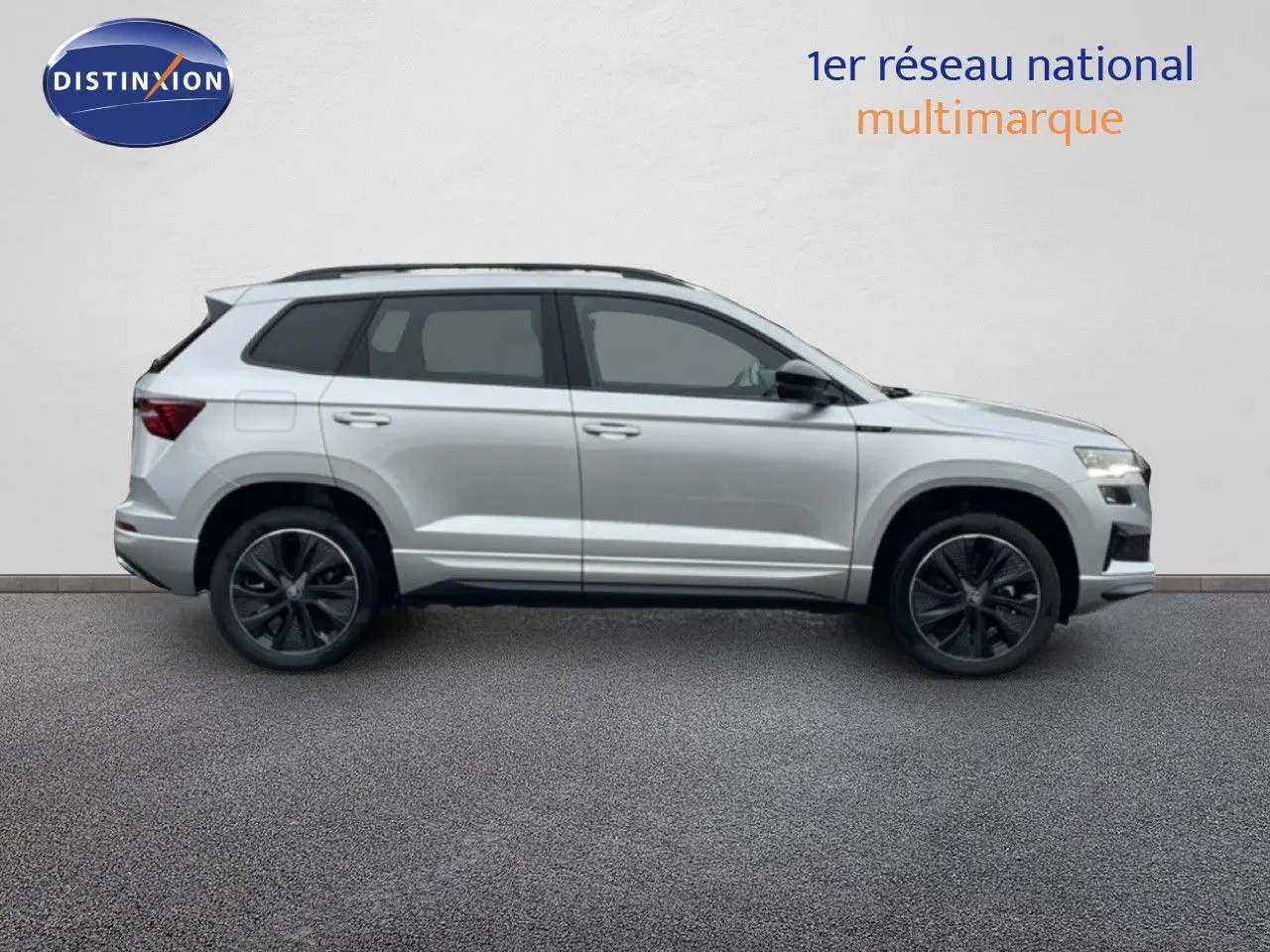 Profil droit d'un Skoda Karoq 2025 gris argent métal, finition Sportline avec jantes noires et toit ouvrant.