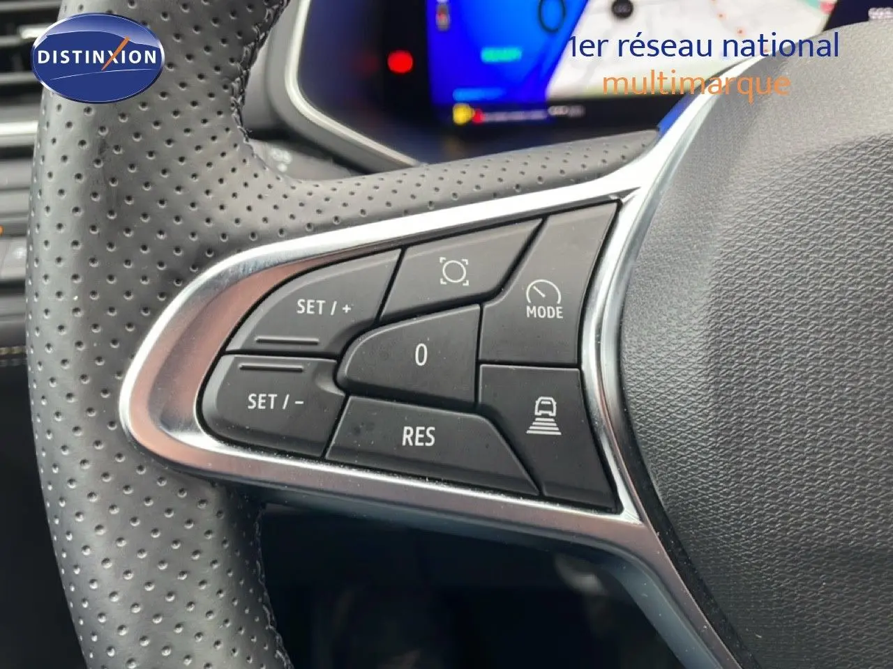 Gros plan sur les commandes à gauche du volant perforé du Renault Symbioz 2025 en noir, avec affichage numérique en arrière-plan.