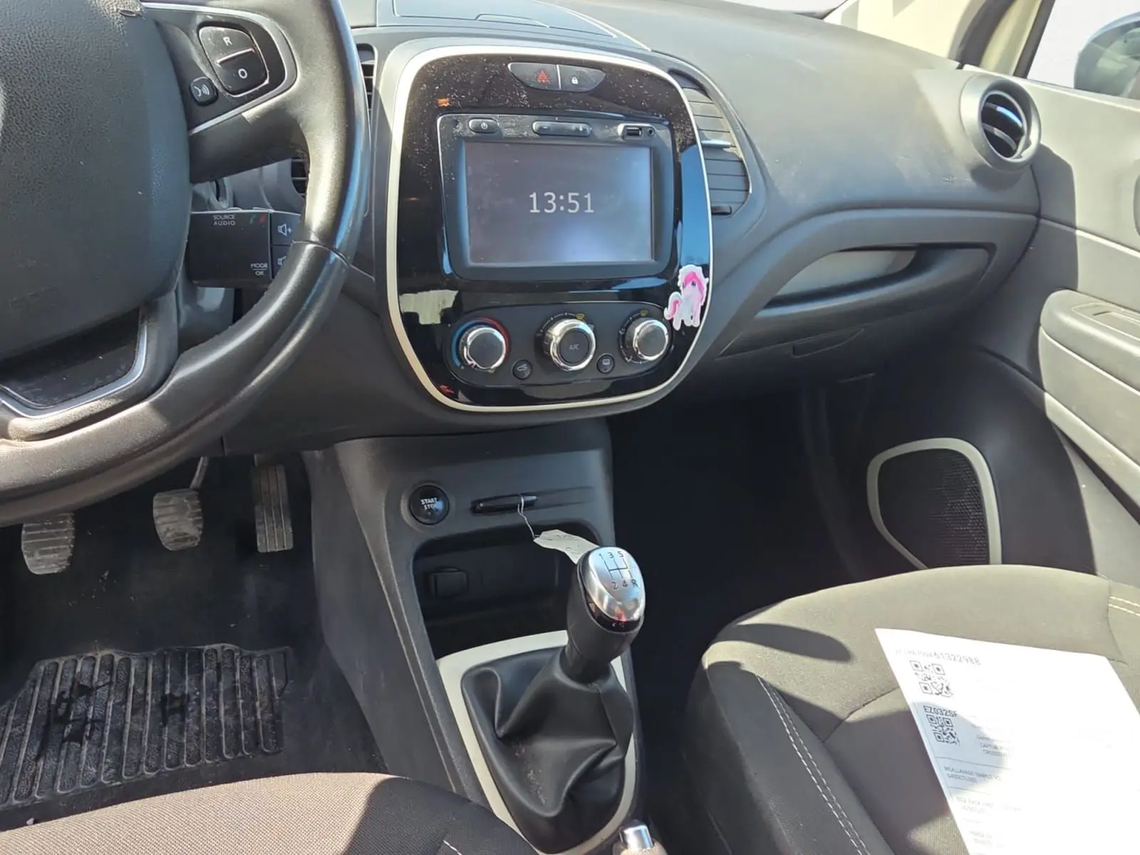 Vue intérieure centrée sur la console centrale et levier de vitesse manuel d’un Renault Captur ivoire de 2018.