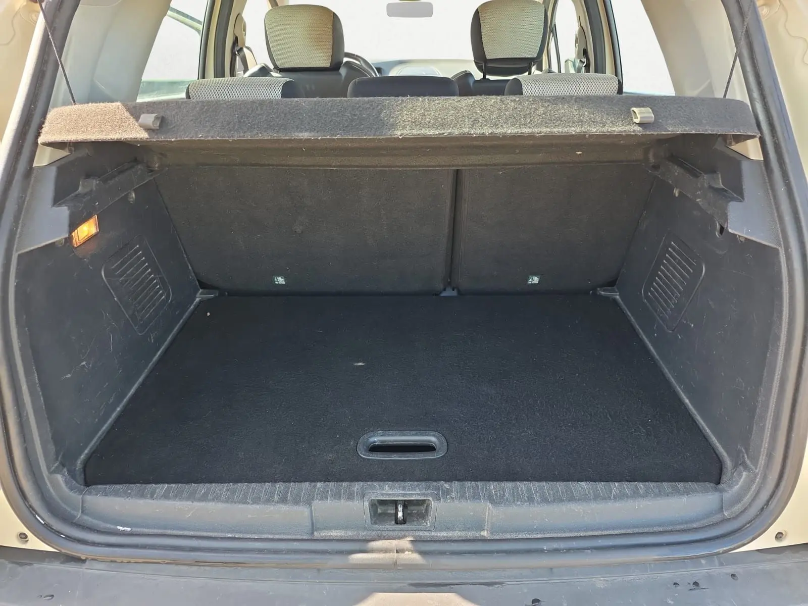 Coffre ouvert vu de l'arrière d'un Renault Captur ivoire 2018, montrant l'espace de chargement et la banquette arrière.