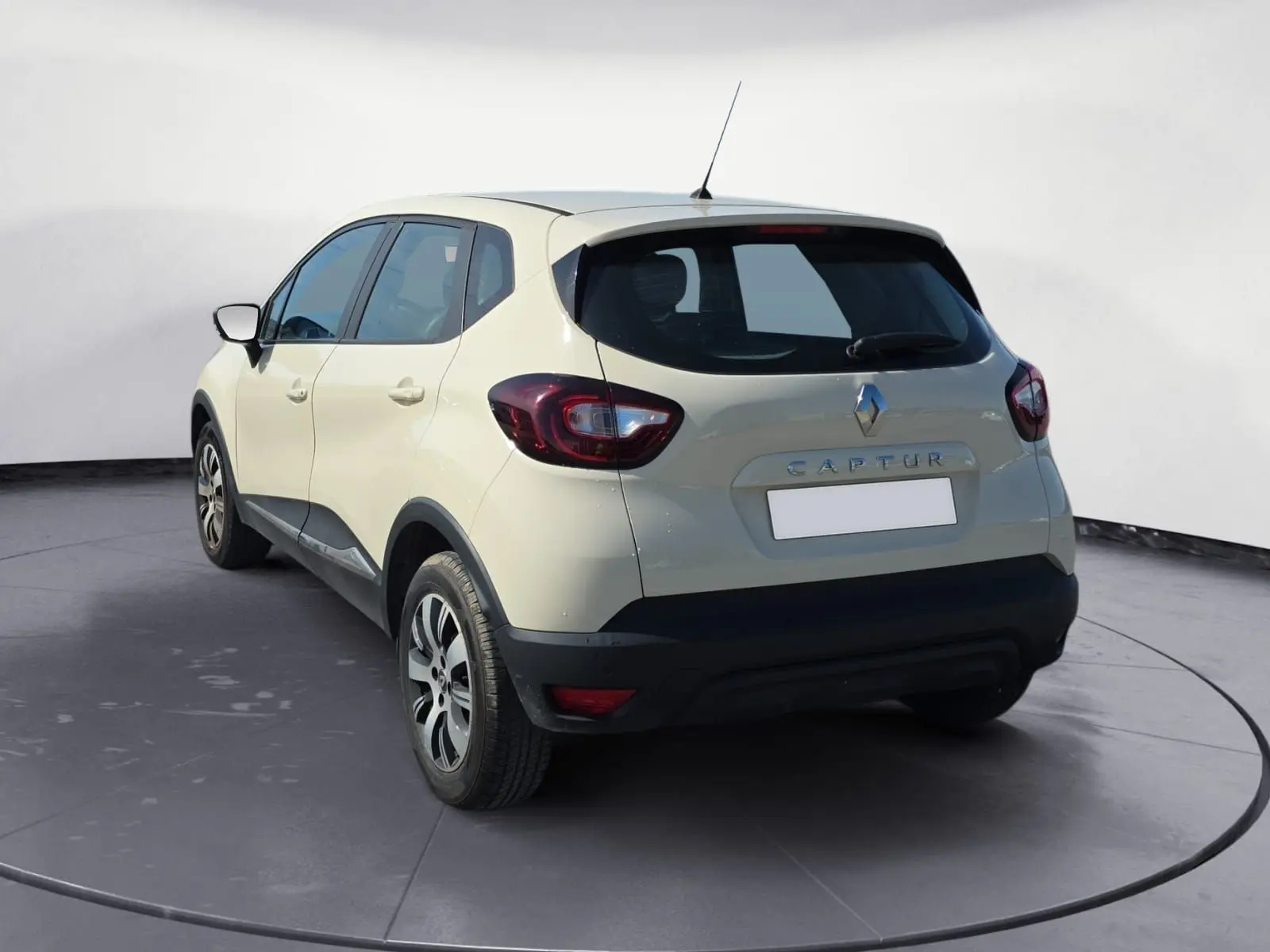 Vue 3/4 arrière droite d’un Renault Captur ivoire 2018 avec jantes alliage et détails noirs sur le bouclier.