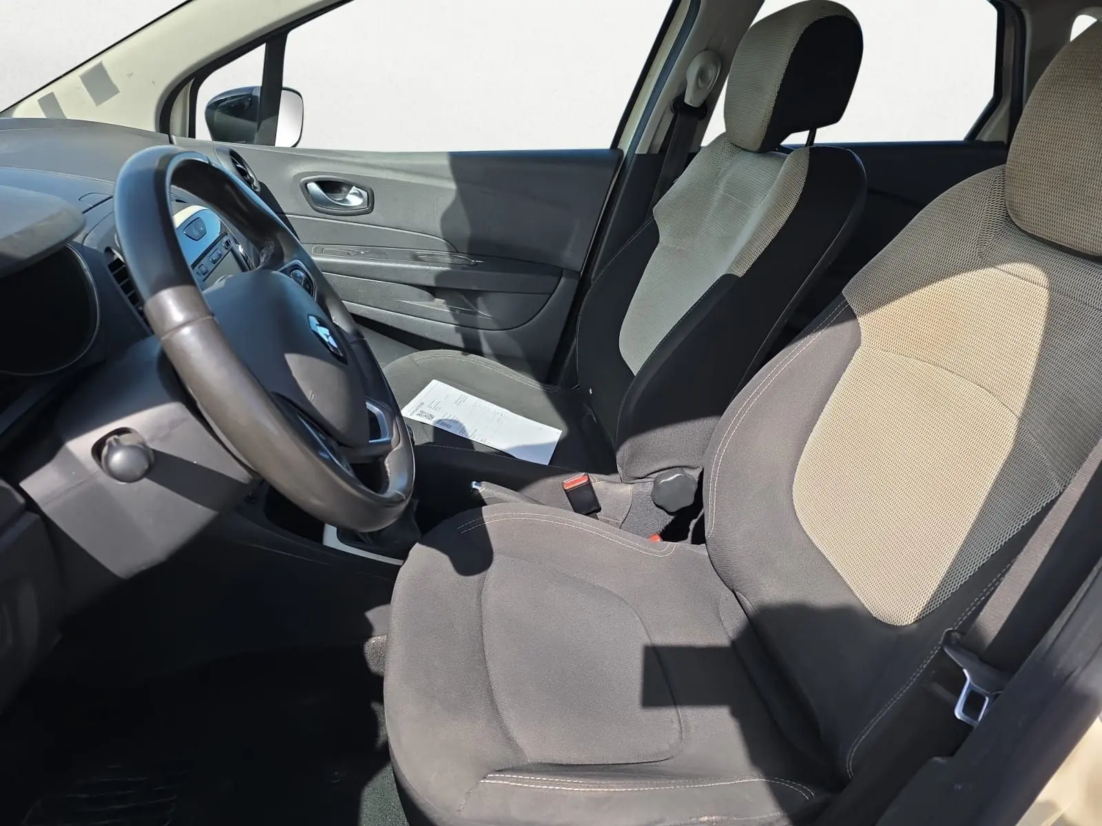 Vue intérieure côté conducteur du Renault Captur ivoire 2018, montrant les sièges bi-ton et le volant cuir.