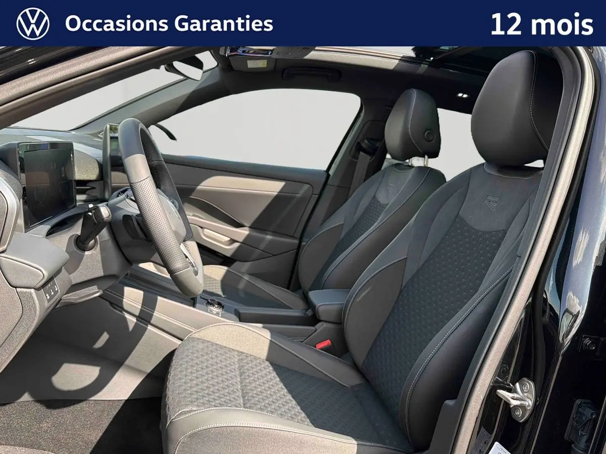 Vue intérieure côté conducteur du Volkswagen T-Roc noir 2026, sièges sport avec logo R et toit ouvrant panoramique visible.