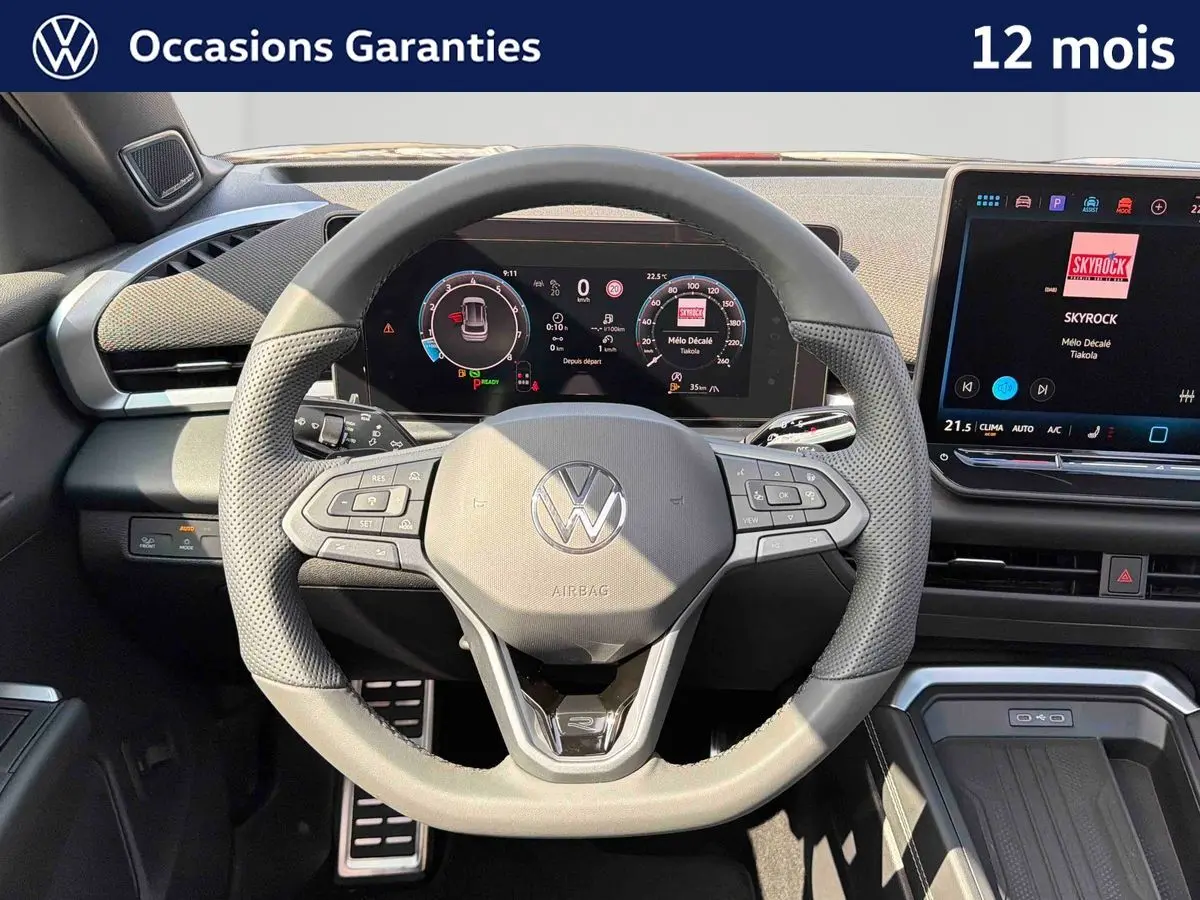 Vue frontale du volant noir perforé et du tableau de bord numérique du Volkswagen T-Roc 2026 avec écran tactile central.