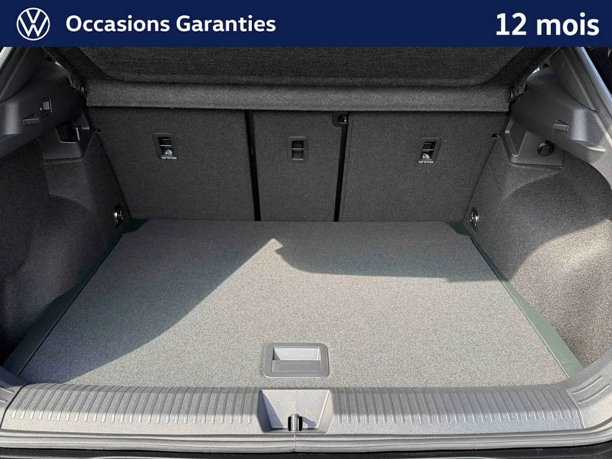 Coffre ouvert du Volkswagen T-Roc noir, vue intérieure montrant l'espace de chargement et la moquette grise.
