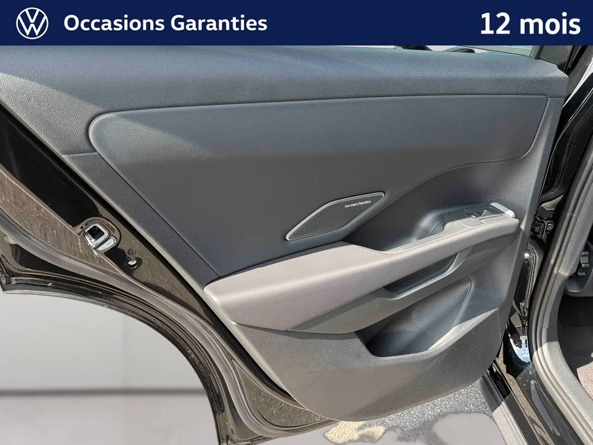 Vue rapprochée de la porte arrière droite noire du Volkswagen T-Roc 2026 avec haut-parleur Harman Kardon intégré.