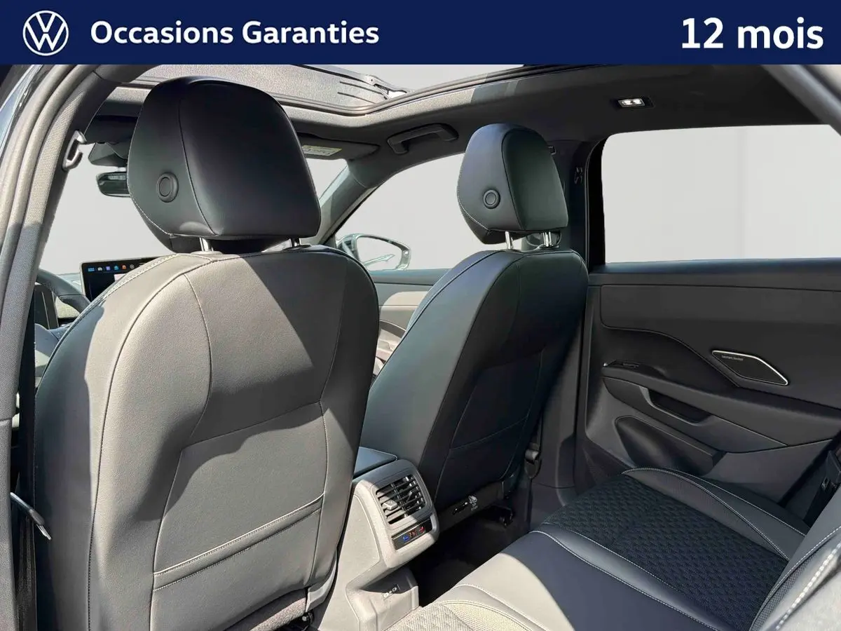Vue arrière intérieure du Volkswagen T-Roc noir 2026, sièges en cuir, toit ouvrant panoramique et aérateurs arrière visibles.