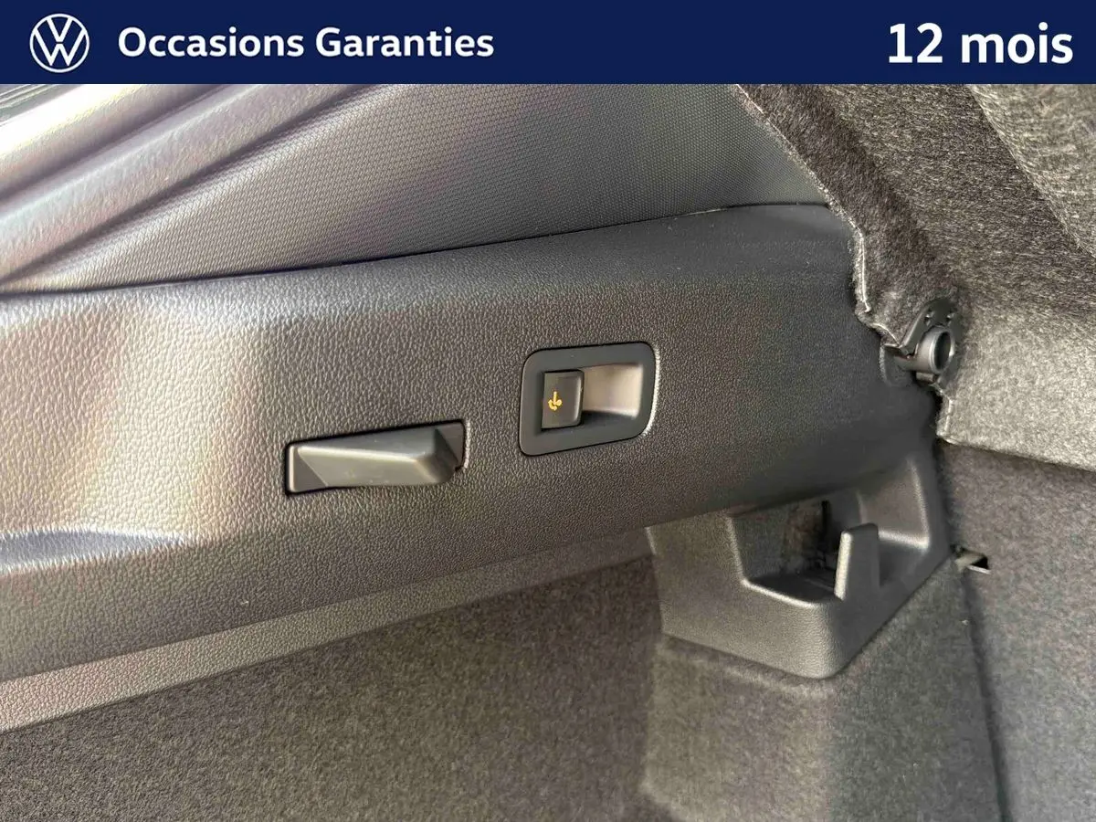 Détail du coffre du Volkswagen T-Roc noir montrant le crochet d'attelage escamotable avec déverrouillage électrique.