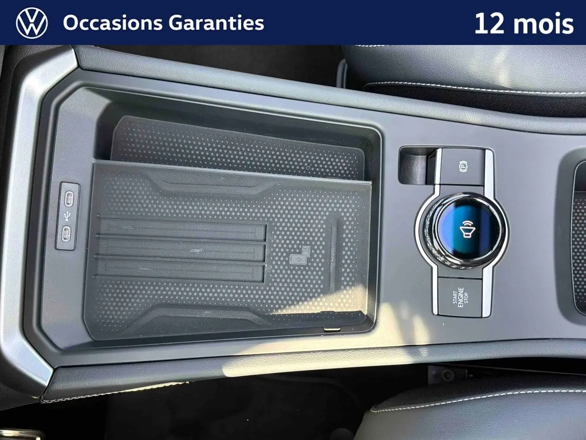 Vue rapprochée de la console centrale noire du Volkswagen T-Roc 2026 avec commande rotative et zone de recharge sans fil.