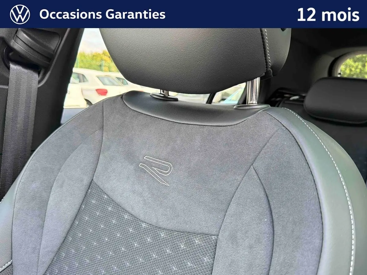Gros plan sur le siège avant gris avec logo R brodé, intérieur du Volkswagen T-Roc 2026 visible en arrière-plan.