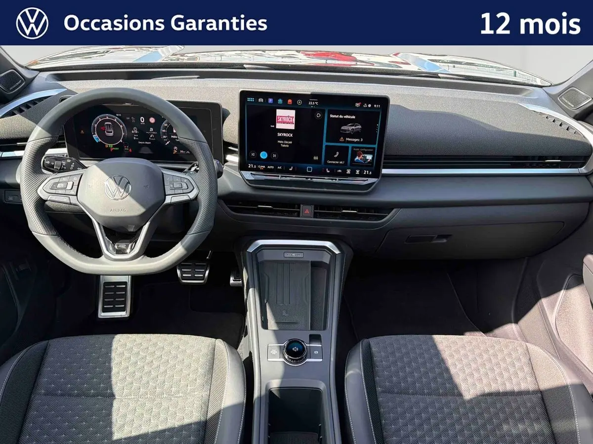 Vue intérieure avant du Volkswagen T-Roc noir, mettant en valeur le tableau de bord digital et la console centrale moderne.