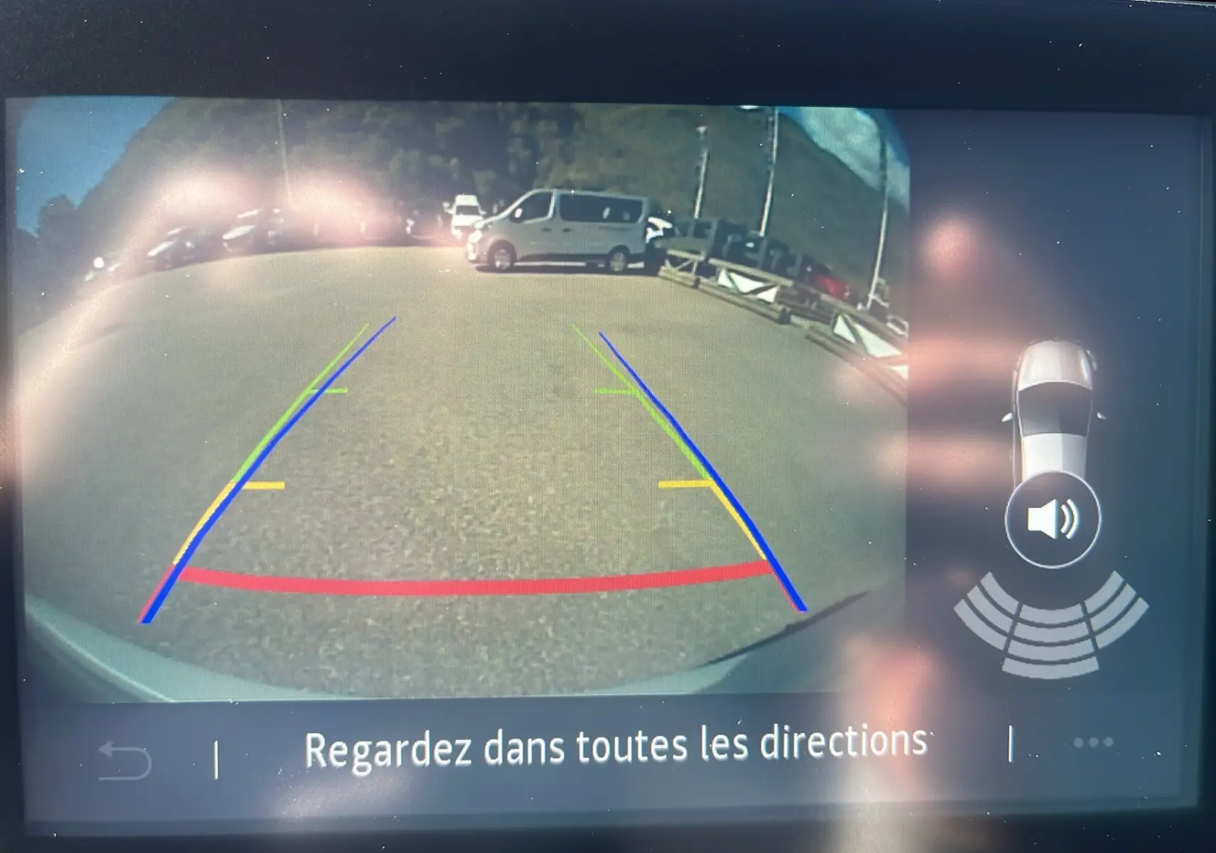 Vue de la caméra de recul d'une Renault Clio V Facelift blanche 2025, montrant les lignes d'aide au stationnement.