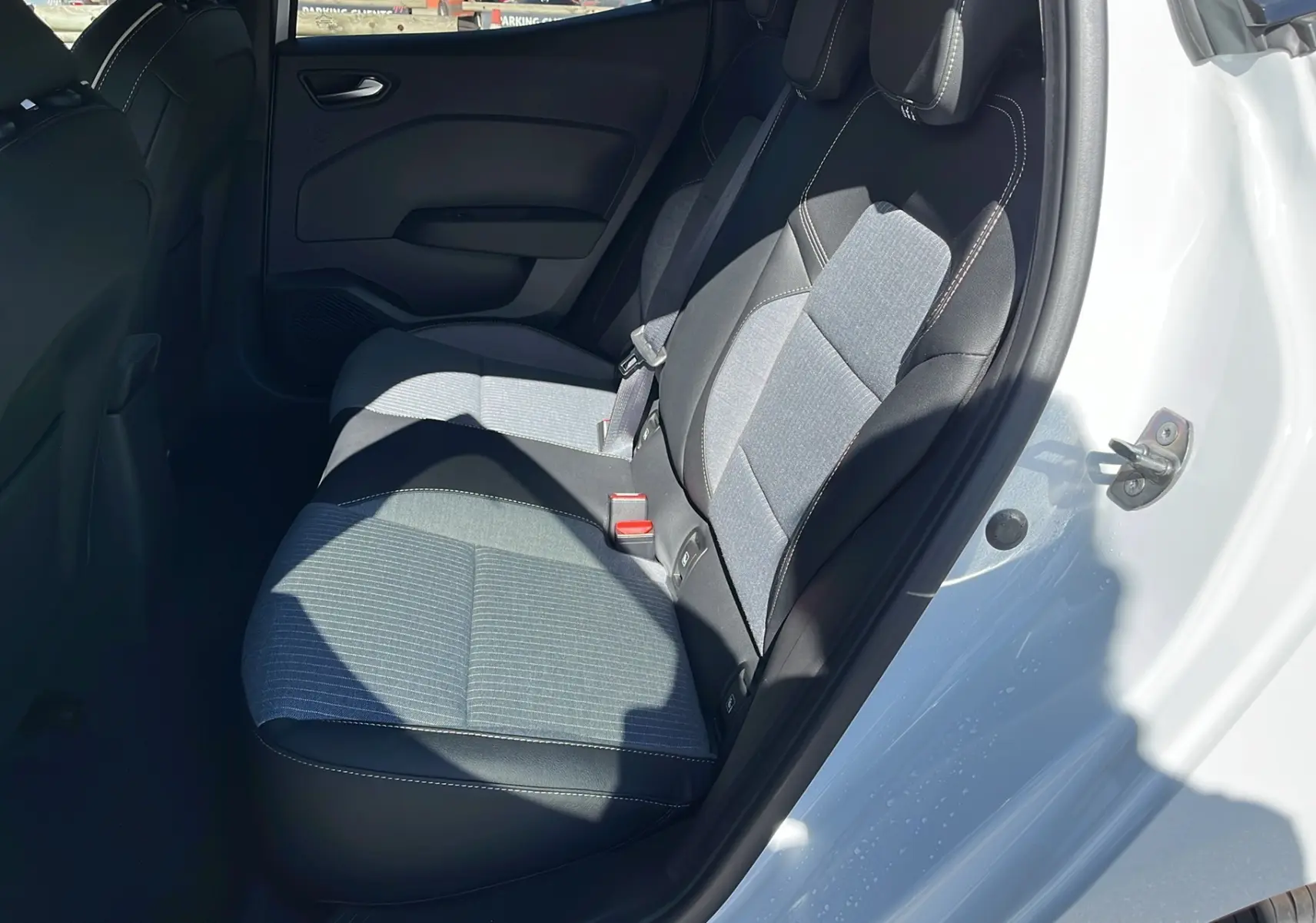 Vue côté droit sur les sièges arrière en tissu gris et noir d'une Renault Clio V Facelift TCe 90 Techno blanche 2025.