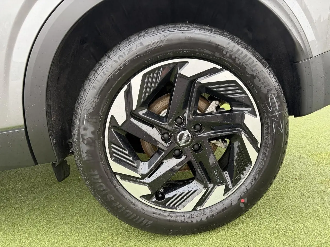 Gros plan sur la jante alliage 18 pouces bicolore noire et argent du Nissan Qashqai III gris foncé.