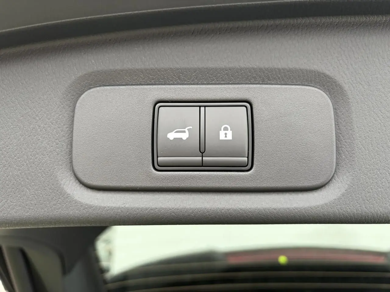 Boutons d'ouverture électrique du hayon et de verrouillage intégrés dans le hayon du Nissan Qashqai III gris foncé.