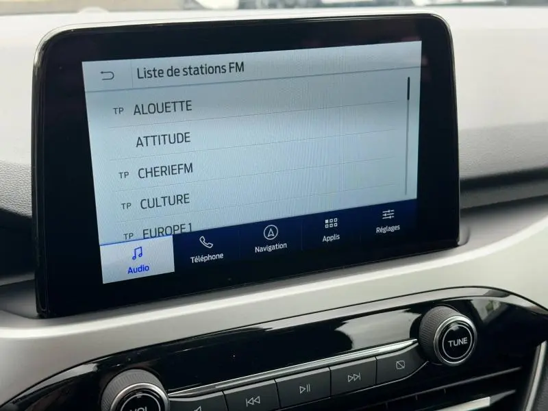 Écran tactile central affichant la liste des stations FM dans l'habitacle du Ford Kuga 2024 gris Solar Métallisée.