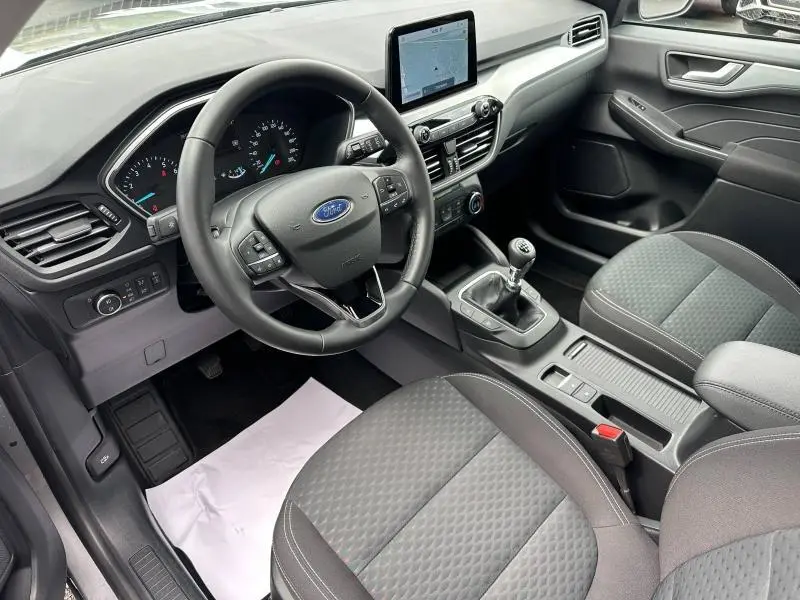 Vue intérieure côté conducteur du Ford Kuga 2024 gris, volant cuir multifonction et boîte manuelle visible.