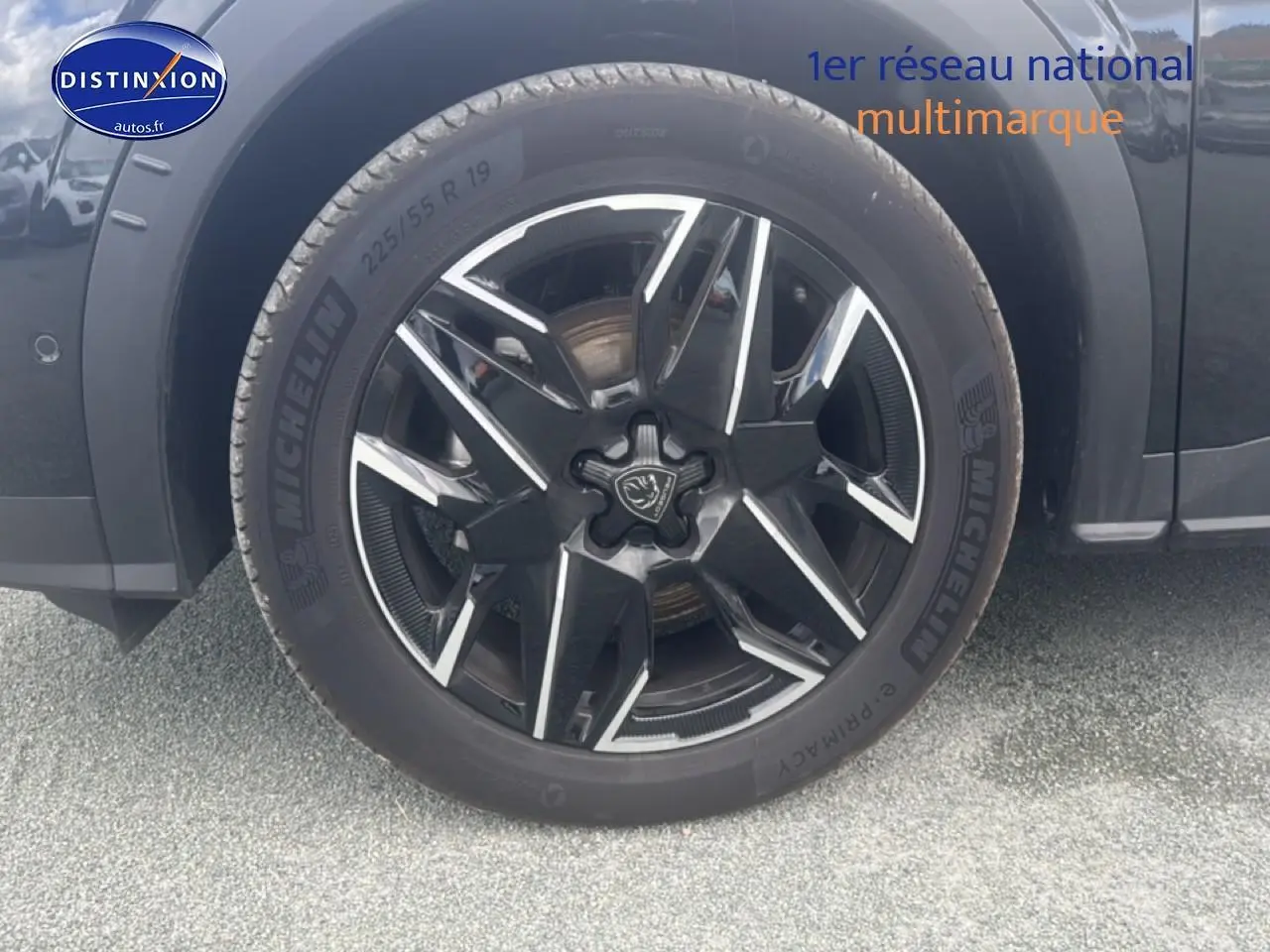 Gros plan sur la roue avant gauche noire du Peugeot 5008 Hybrid 145 allure e-dcs6 avec jante alu bicolore.