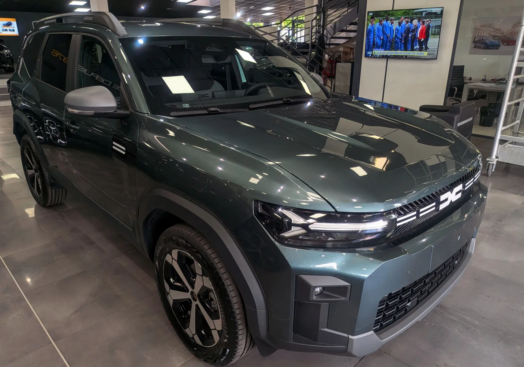 SUV Dacia Bigster vert cèdre en 3/4 avant droit, avec calandre lumineuse et jantes noires bicolores.