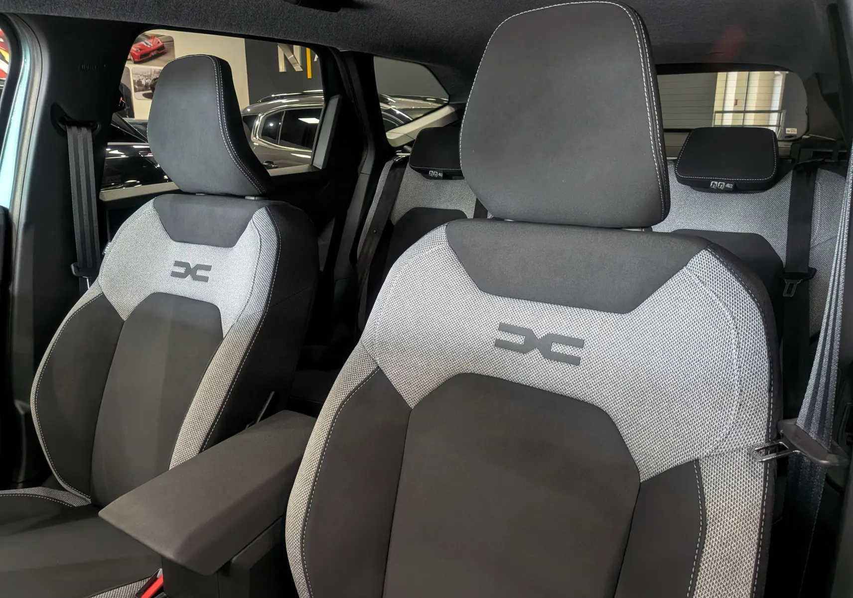 Gros plan sur les sièges avant en tissu gris et noir du Dacia Bigster 2026, avec logo distinctif brodé.
