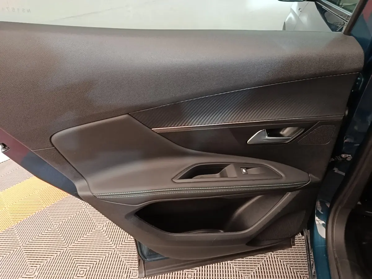 Vue intérieure côté gauche de la porte arrière bleu du Peugeot 3008 1.6 HYBRID avec garniture noire et surpiqûres.