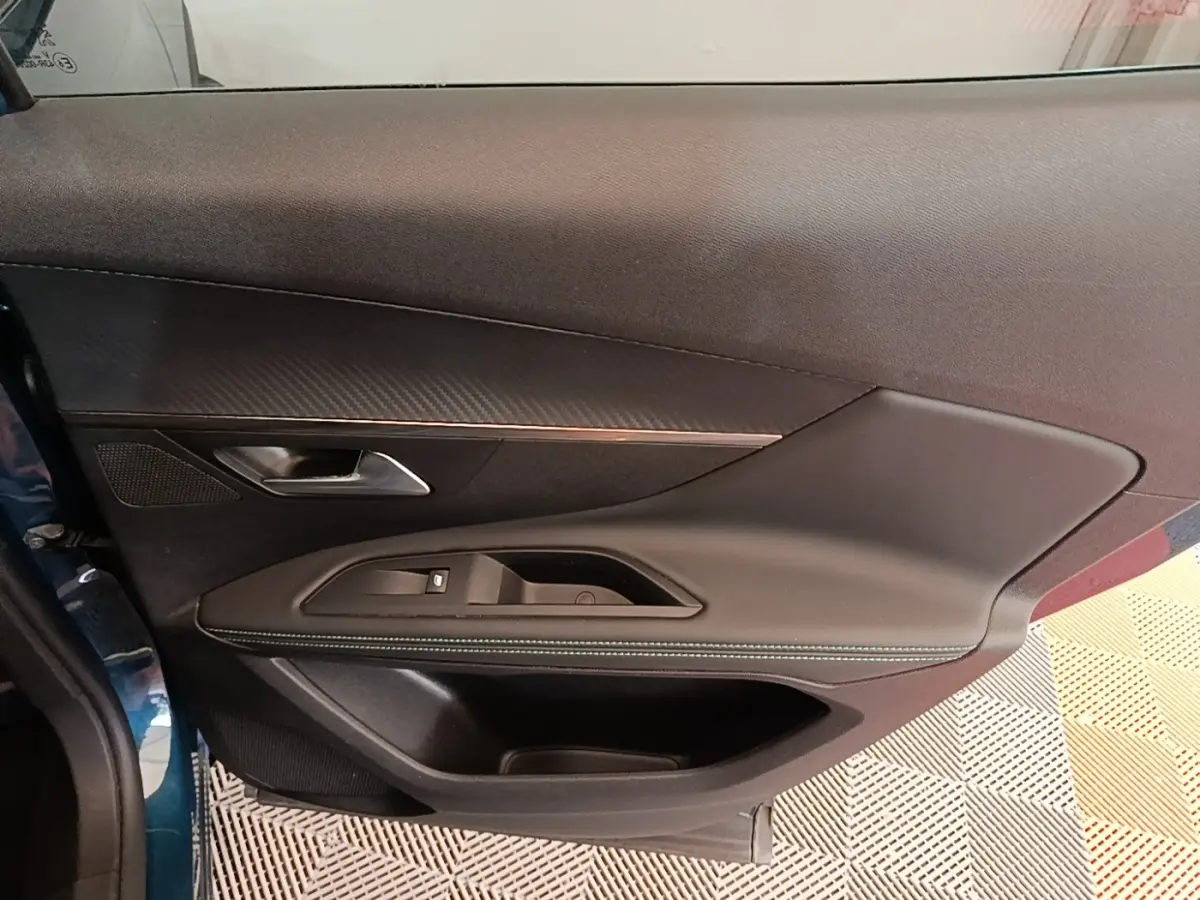 Vue rapprochée de la porte avant gauche bleu métallisé du Peugeot 3008 1.6 Hybrid avec garniture noire et surpiqûres blanches.