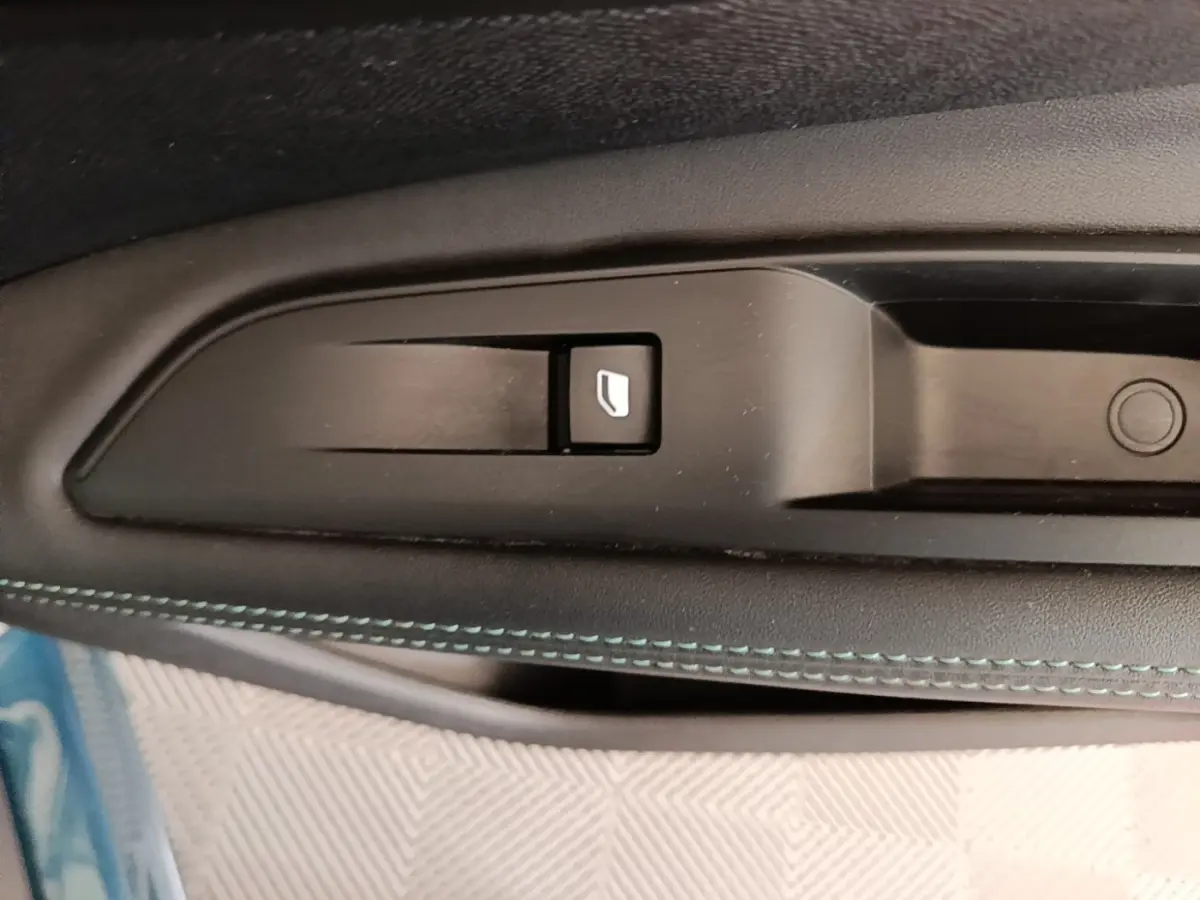 Gros plan sur le bouton de verrouillage des portes sur la portière intérieure noire avec surpiqûres bleues du Peugeot 3008 hybride.