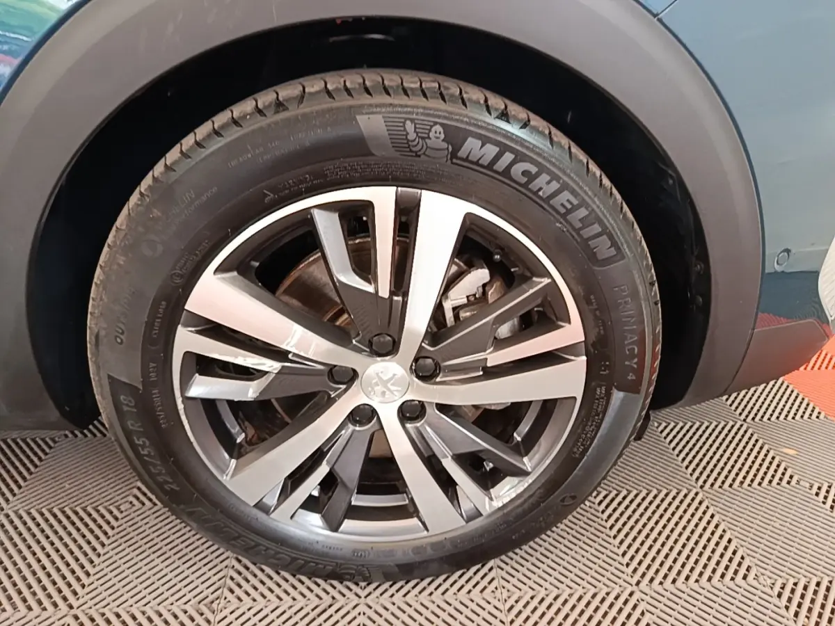 Gros plan sur la roue avant droite du Peugeot 3008 bleu, mettant en valeur la jante alliage et le pneu Michelin.