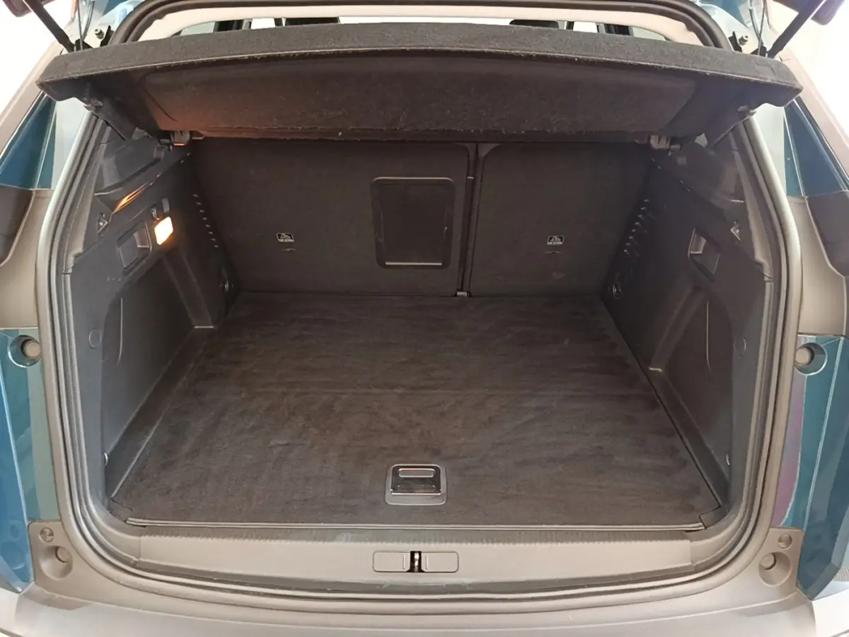 Coffre ouvert vu de l'arrière d'un Peugeot 3008 bleu, montrant l'espace de chargement et la banquette arrière rabattue.