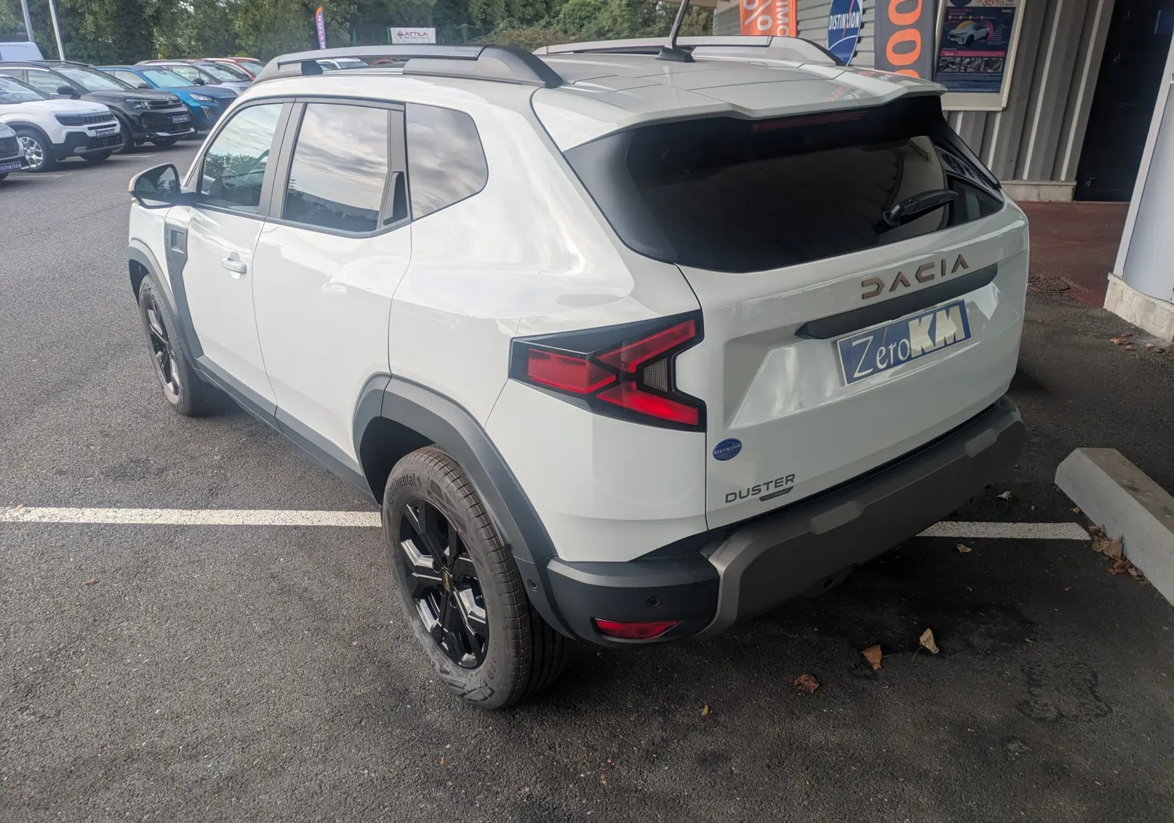 Vue 3/4 arrière droite du Dacia Duster Hybrid 155 Extreme blanc glacier avec jantes noires et vitres arrière surteintées.