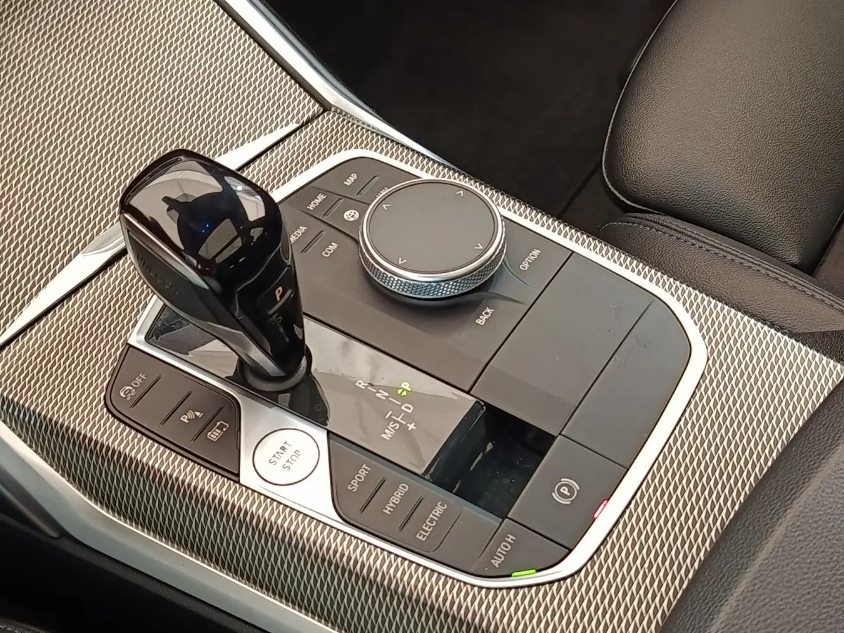 Gros plan sur la console centrale de la BMW Série 3 320e hybride, avec levier de vitesses et commandes mode de conduite.