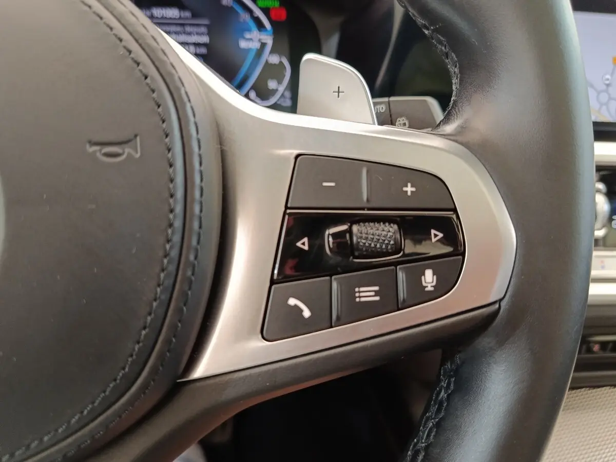 Gros plan sur les commandes multifonctions côté droit du volant cuir de la BMW Série 3 320e gris foncé hybride 2022.