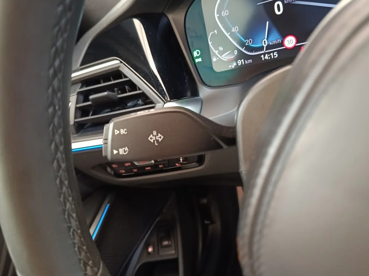 Détail du combiné d'instruments et commande au volant côté gauche dans l'habitacle d'une BMW Série 3 gris foncé hybride rechargeable.