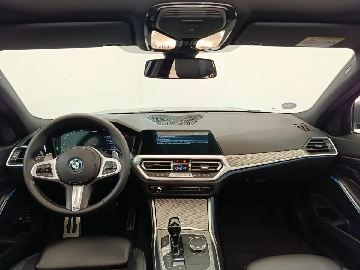 Vue intérieure avant de la BMW Série 3 320e M Sport 2022, tableau de bord moderne avec écran tactile et volant cuir noir.