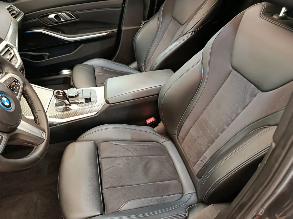 Vue intérieure côté conducteur de la BMW Série 3 320e gris foncé, sièges sport cuir et alcantara avec surpiqûres M tricolores.