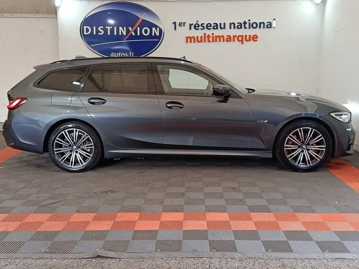 Vue de profil côté gauche d'une BMW Série 3 Touring 320e M Sport gris foncé avec jantes alliage et vitres teintées.