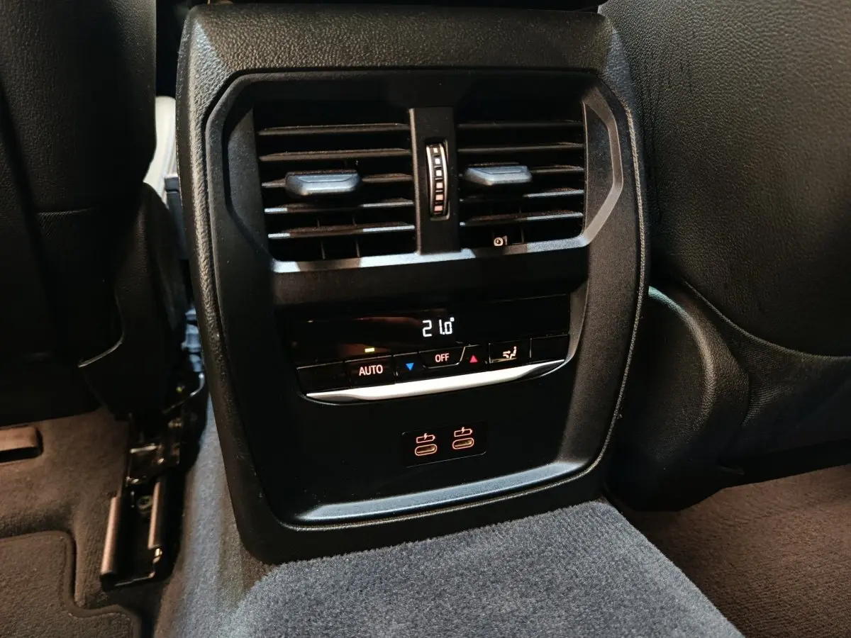Vue rapprochée de la console centrale arrière noire avec ventilation, commandes climatisation et ports USB de la BMW Série 3 320e.