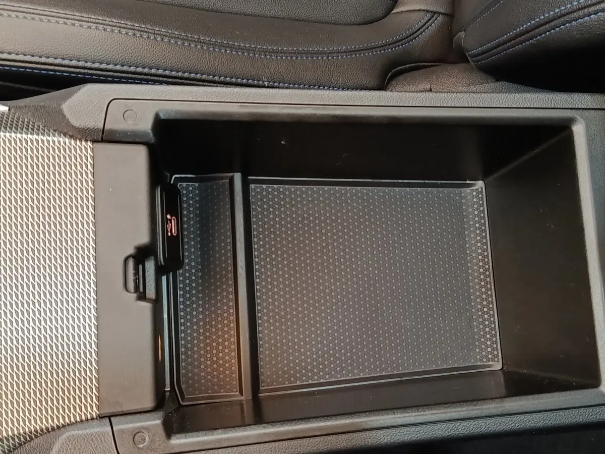 Gros plan sur la console centrale noire de la BMW Série 3 320e M Sport 2022, avec compartiment de rangement ouvert.