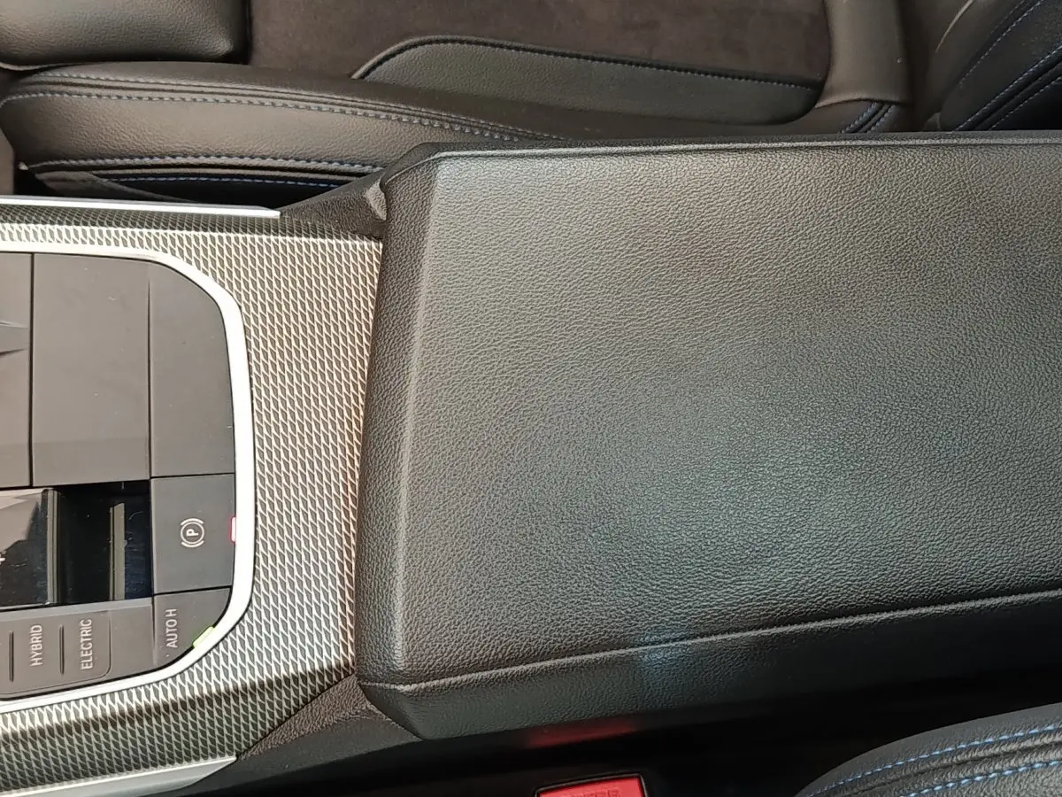 Vue rapprochée de la console centrale en cuir noir et inserts métalliques texturés de la BMW Série 3 320e M Sport hybride.