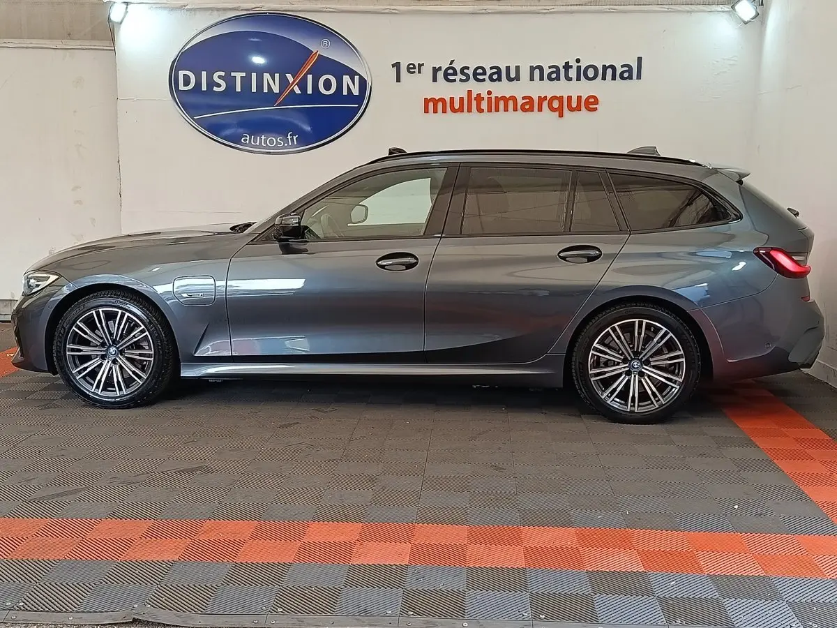 BMW Série 3 320e M Sport gris foncé vue de profil côté gauche, break hybride avec jantes sport et toit noir.