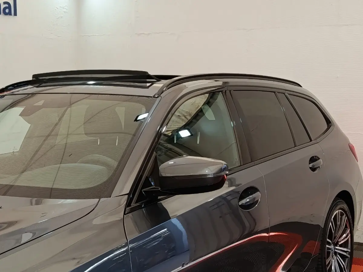 Vue de profil droit sur la BMW Série 3 320e M Sport hybride gris foncé avec toit ouvrant et jantes sport.