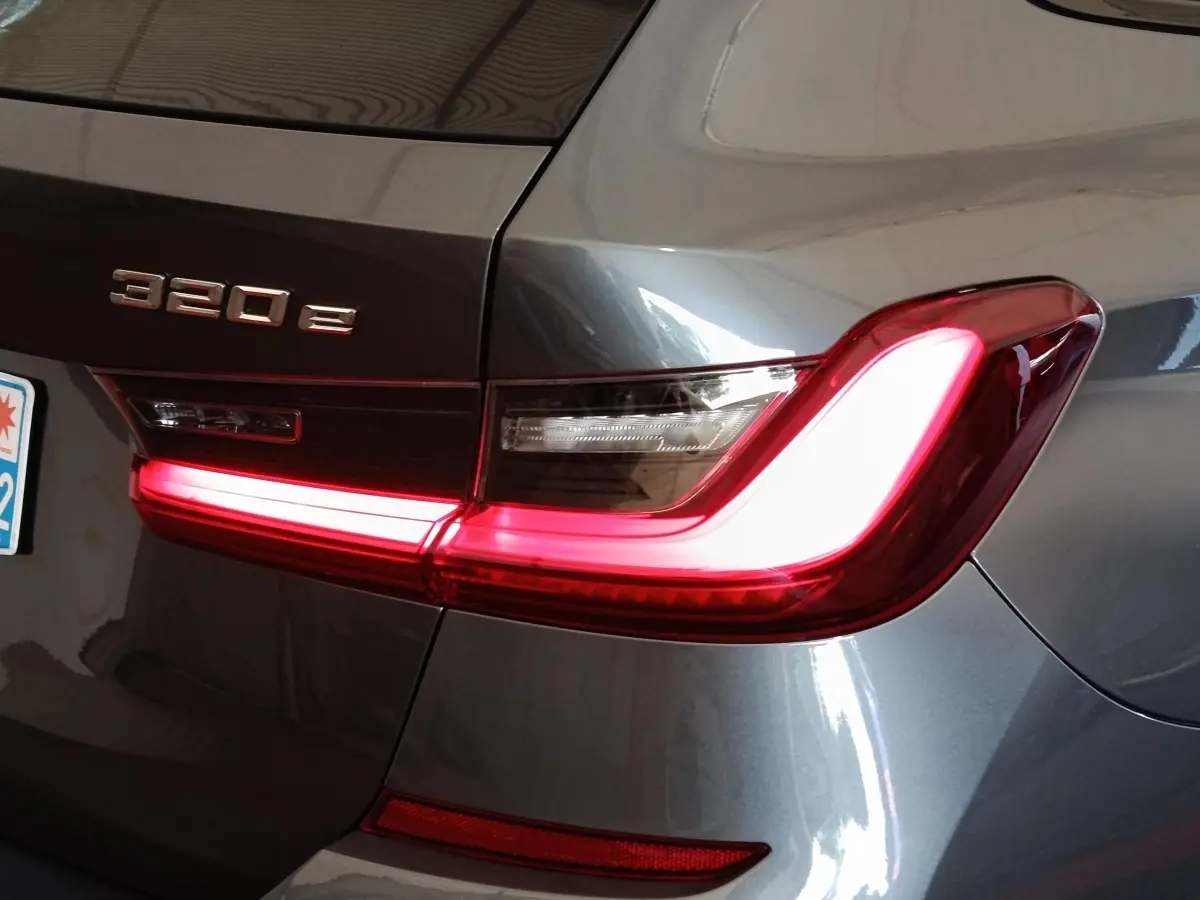 Gros plan sur l'arrière droit d'une BMW Série 3 320e gris foncé avec feu arrière LED allumé et logo visible.