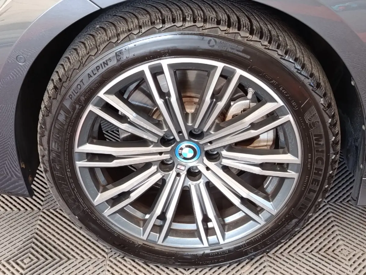Gros plan sur la jante alliage gris et le pneu Michelin d’une BMW Série 3 320e gris foncé, vue côté gauche.
