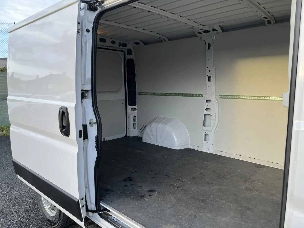 Vue latérale gauche d’un Opel Movano Fourgon blanc 2024 avec porte coulissante ouverte montrant l’intérieur vide et plancher noir.
